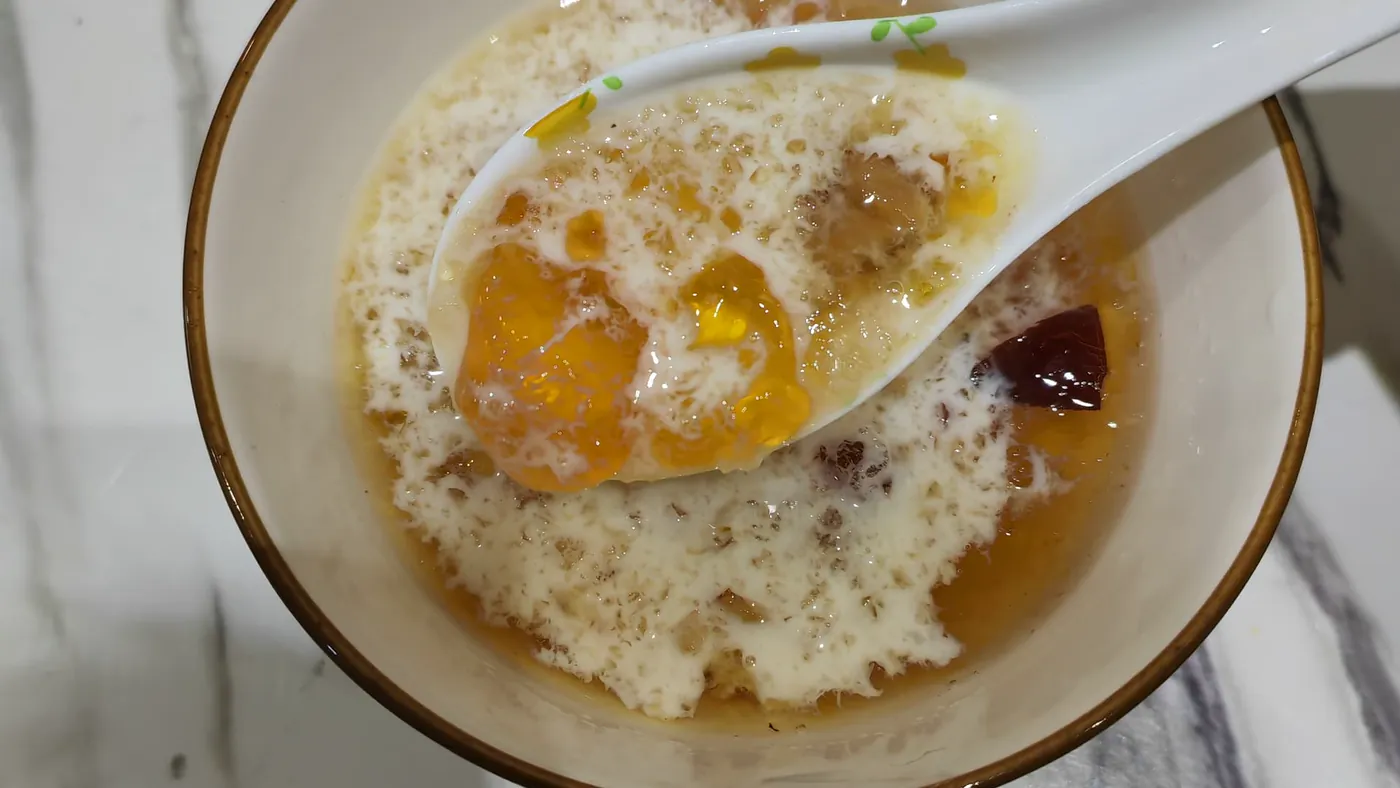 汤匙从白碗里捞起金黄的桃胶，牛奶淋在上面，旁边一颗红枣。