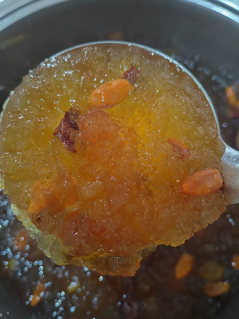 锅里刚煮好的桃胶雪燕，大汤勺捞起一勺金黄透亮的桃胶，看得到红枣和枸杞。
